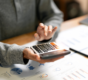 Person tippt am Taschenrechner